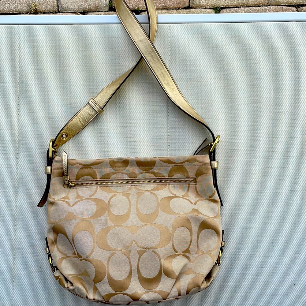 Coach crossbody with gold leather trim and hardware.